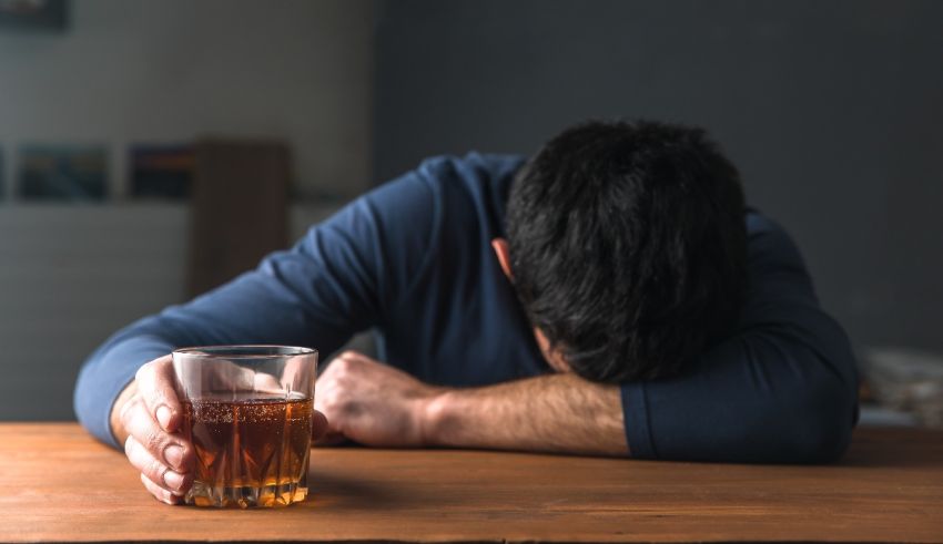 A man leaning over a table with a glass of alcohol.