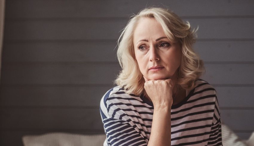 A woman sitting on a couch with her hand on her chin.