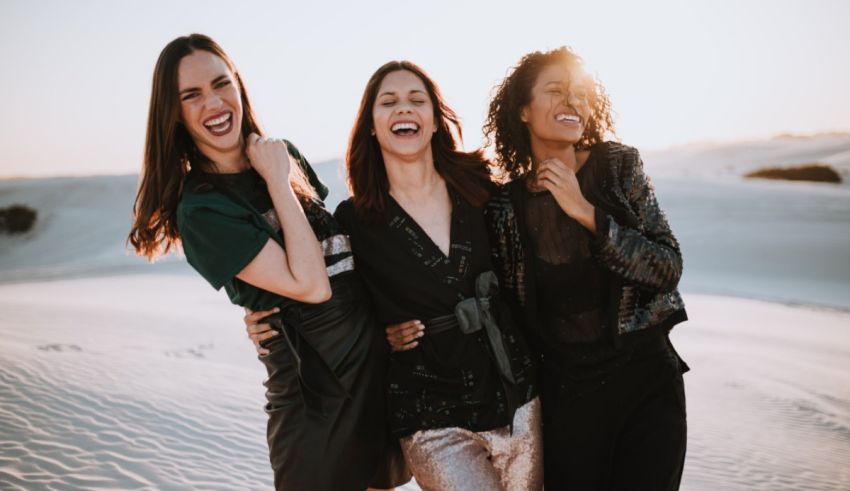Three women laughing in the sand dunes.