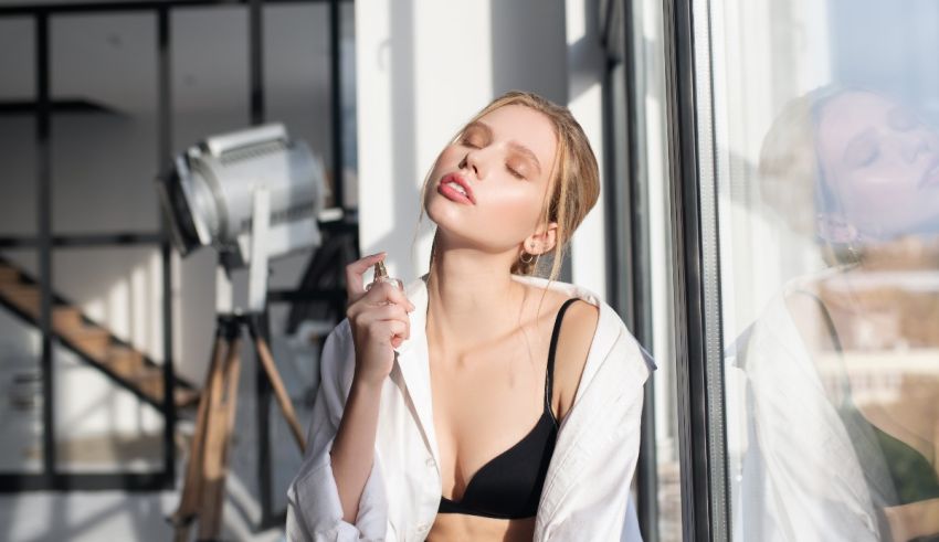 A woman is sitting on a window sill while brushing her teeth.