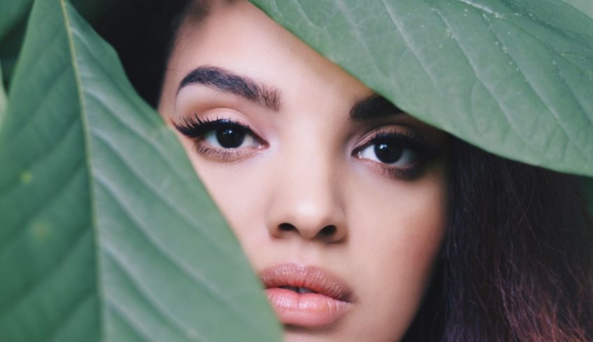 A woman peeking out from behind a leaf.