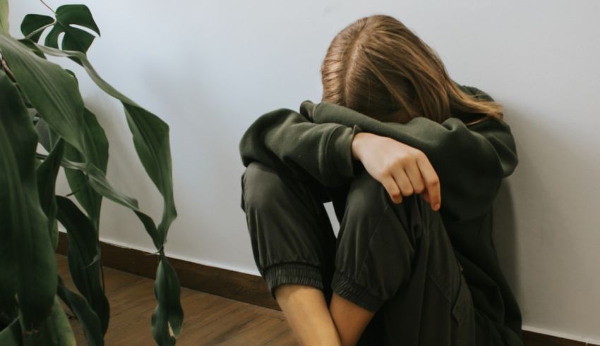 A woman sitting on the floor with her hands on her knees.