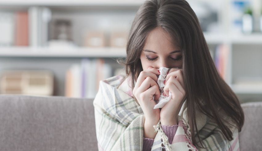 A woman blowing her nose while sitting on a couch.