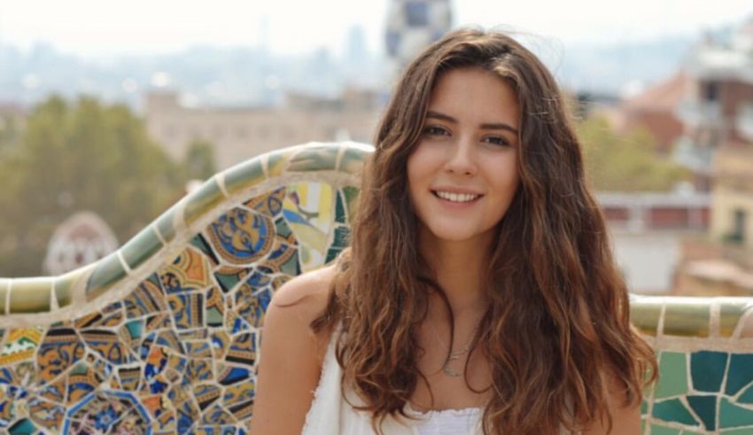 A young woman smiling in front of a tiled wall.