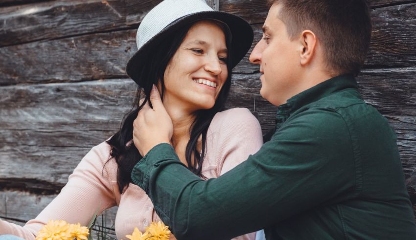 A man and woman are sitting in front of a wooden wall.