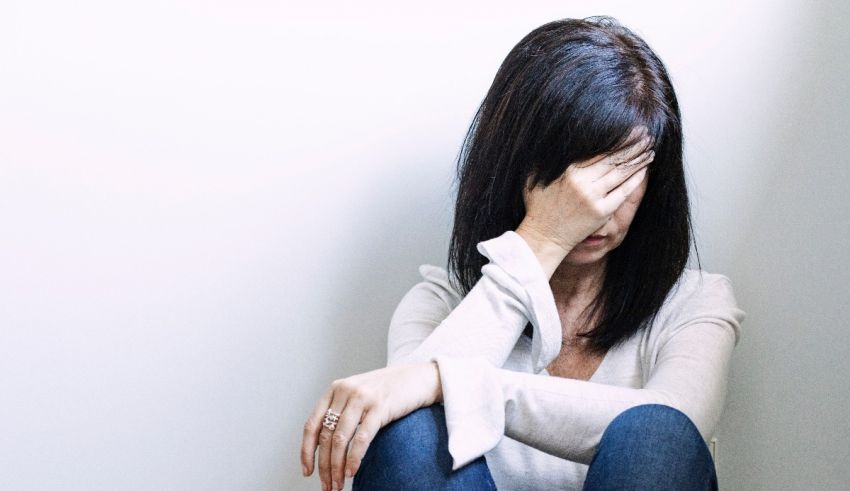 A woman sitting on the floor with her hands on her face.