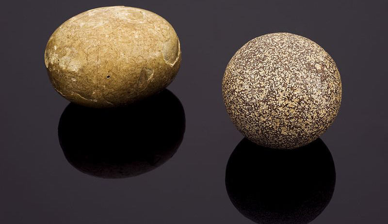 Two stone eggs on a black surface.