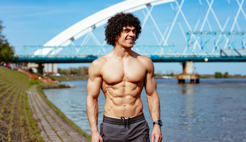A man standing in front of a river with a bridge in the background.
