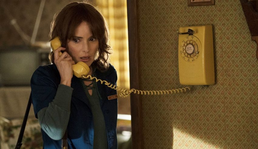 A woman talking on a yellow telephone in a room.