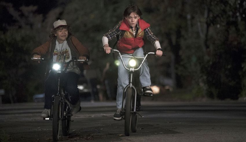 Two people riding bicycles at night in a dark street.