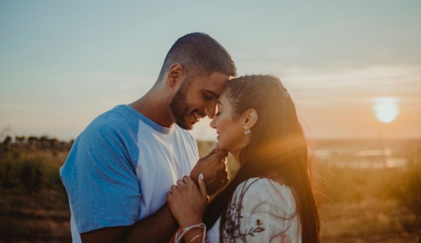 A couple embracing at sunset in a field.