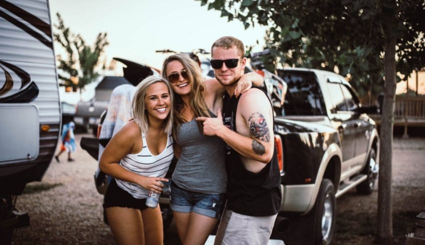 Three people posing for a picture in front of an rv.