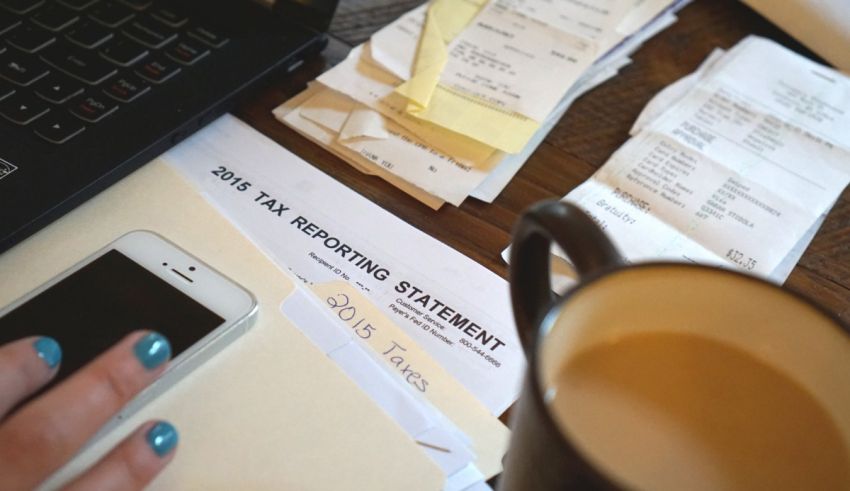 A person is sitting at a desk with papers and a cell phone.