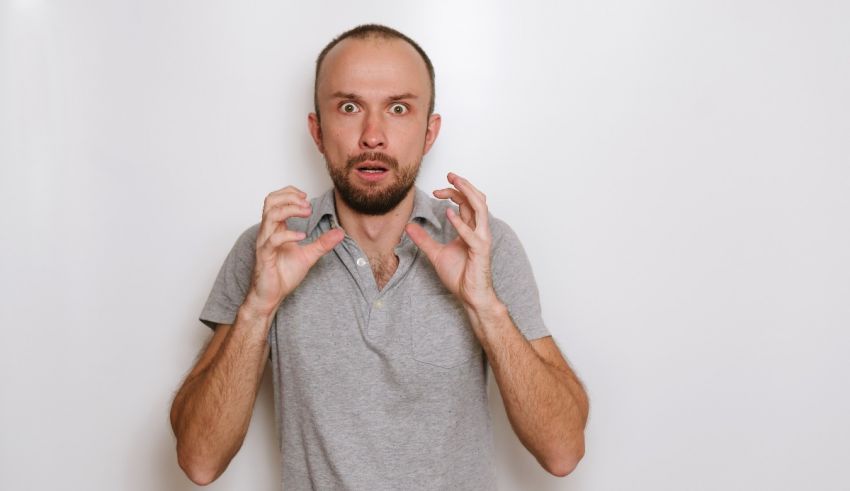A man in a gray shirt is making a face with his hands.