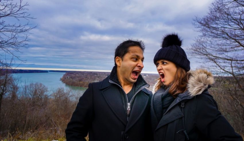 A man and woman are laughing while standing in front of a lake.