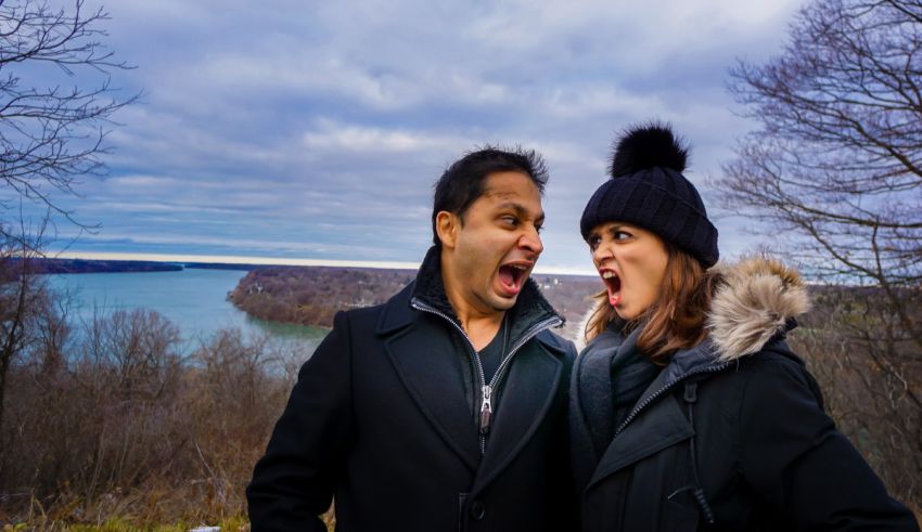 A man and a woman are standing in front of a lake.
