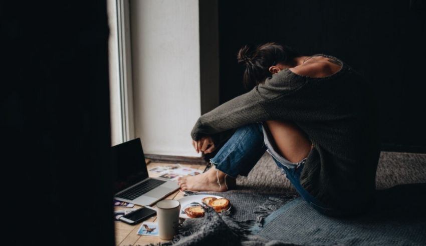 A woman sitting on the floor with a laptop and a cup of coffee.