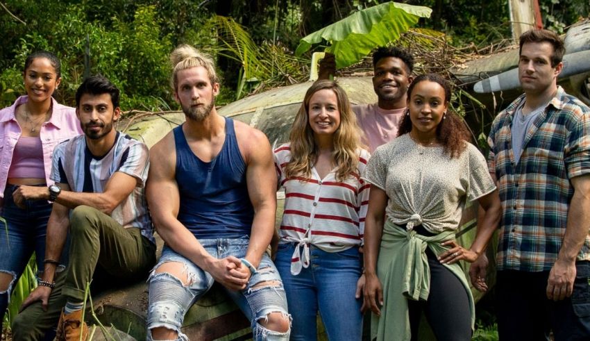 A group of people posing in front of an old airplane.