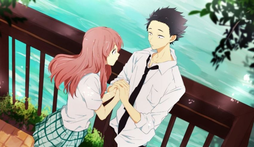 A girl and a boy standing on a railing next to a body of water.