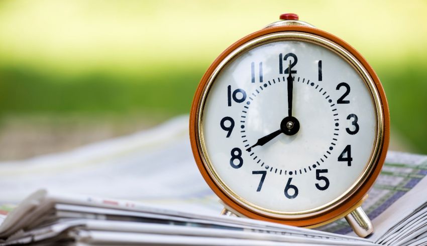 A clock sits on top of a stack of newspapers.
