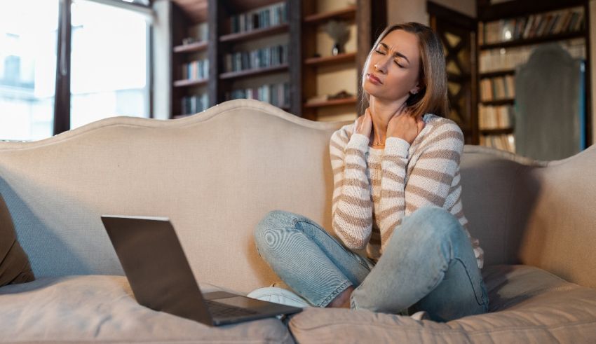 A woman sitting on a couch with a laptop on her lap.