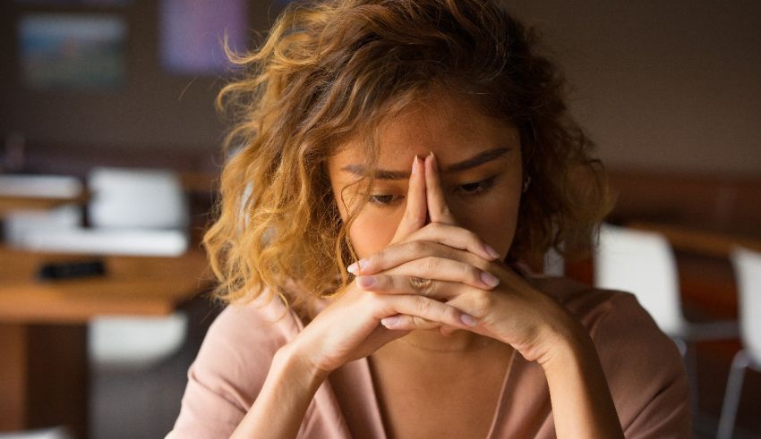 A woman sitting at a table with her hands on her face.