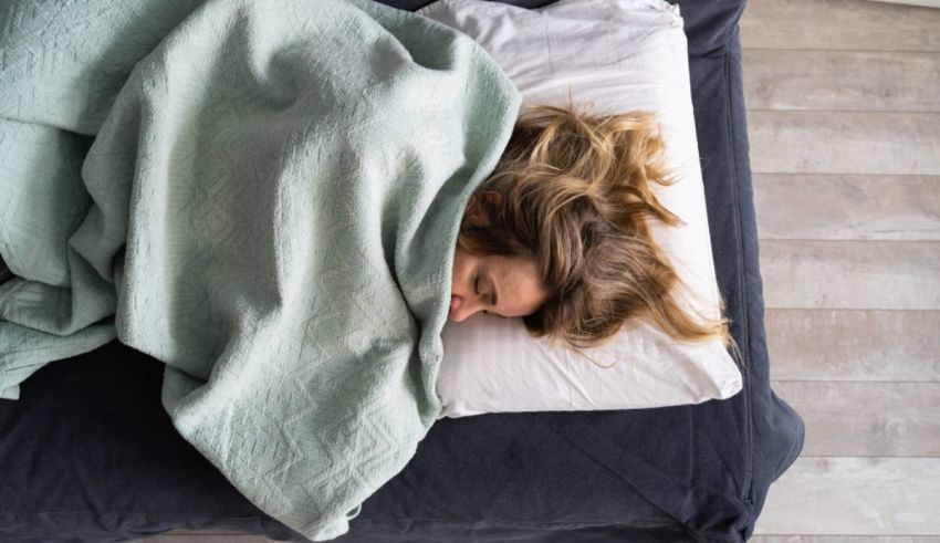 A woman sleeping on a bed with a green blanket.