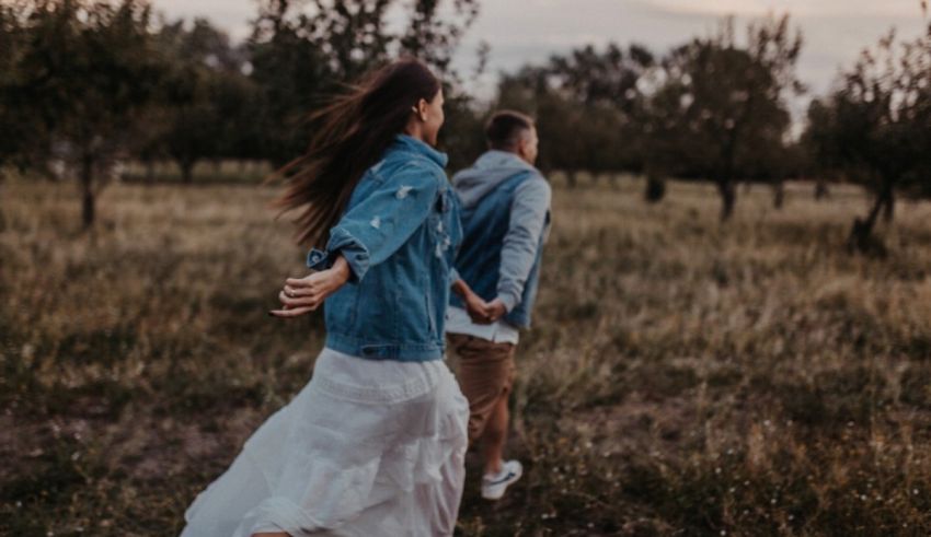 A couple walking through an orchard at sunset.