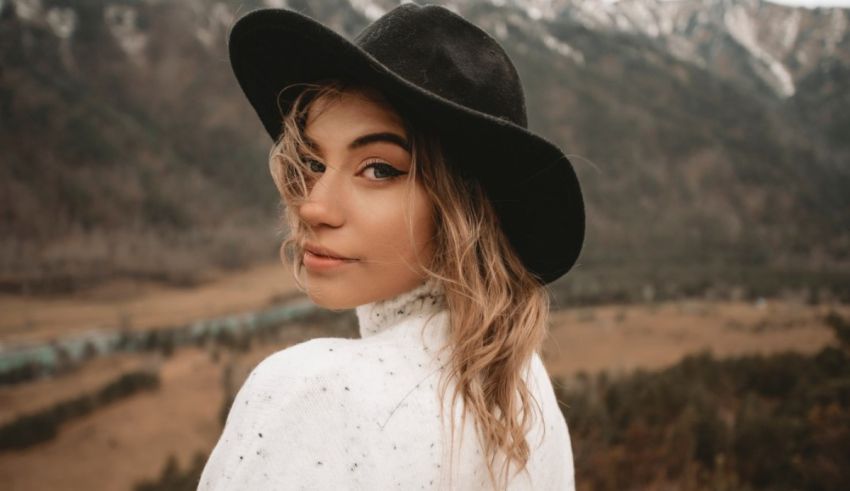 A woman wearing a hat in front of a mountain.