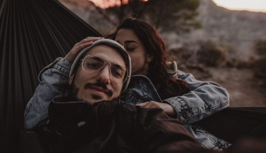 A couple laying in a hammock at sunset.