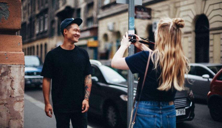 A man is taking a picture of a woman on the street.