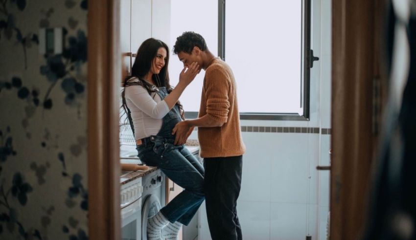 A man and woman standing in a kitchen looking at each other.