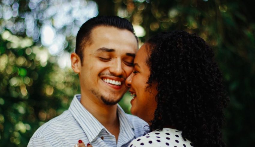A man and woman are embracing in front of a tree.