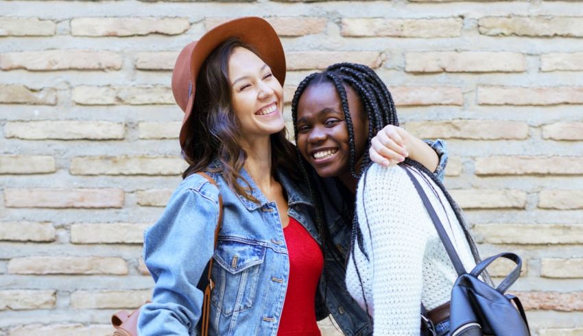 Two young women hugging in front of a brick wall.