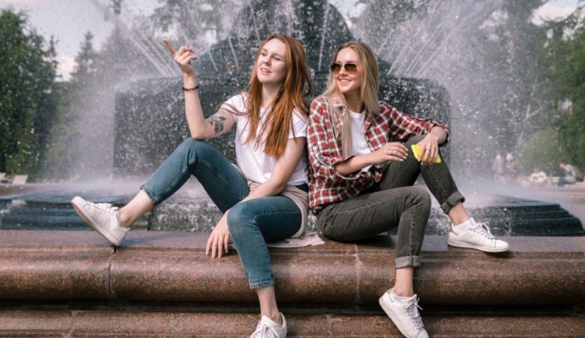 Two young women sitting in front of a fountain.