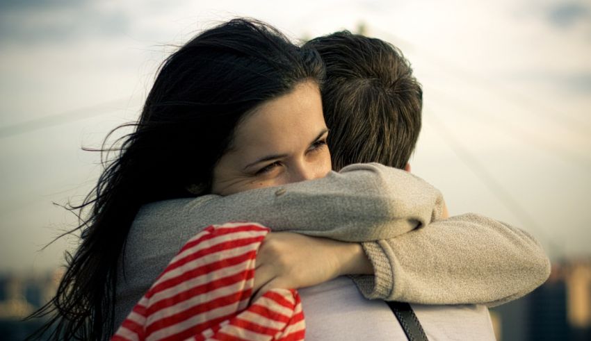 A man and woman hugging in front of a city.