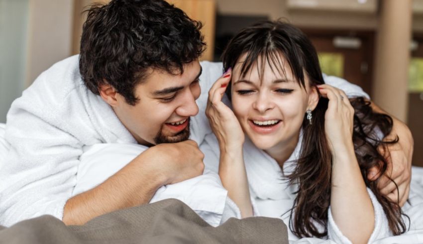 A man and woman laying on a bed laughing.