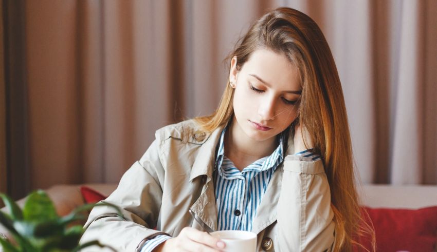 A woman is sitting on a couch with a cup of coffee.