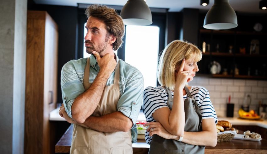A man and woman in aprons standing in the kitchen.