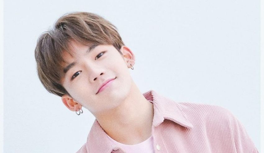 A young man in a pink shirt posing for a photo.