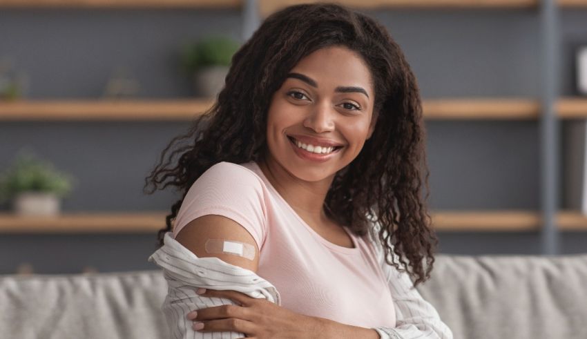 A young woman with a bandage on her arm is sitting on a couch.