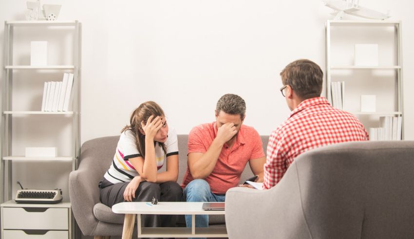 A man and woman sitting on a couch talking to each other.