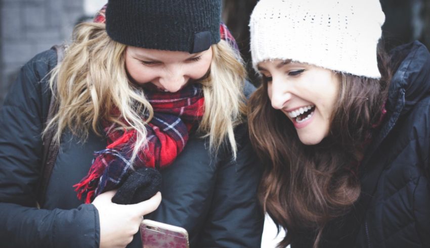 Two women looking at a cell phone in the snow.