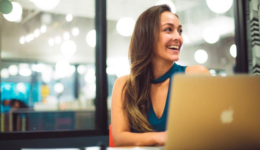 A smiling woman working on a laptop in an office.