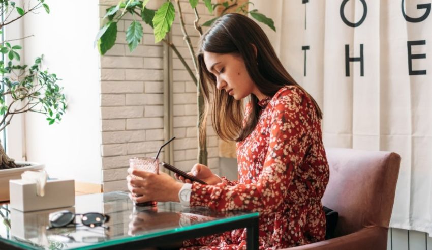 A woman sitting at a table looking at her phone.