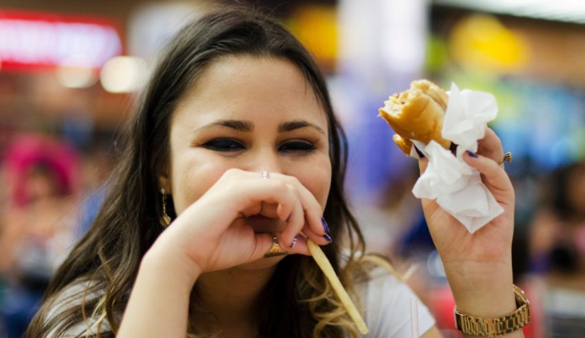 A woman eating a hot dog with chopsticks.