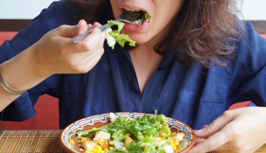 A woman eating a salad with a fork.