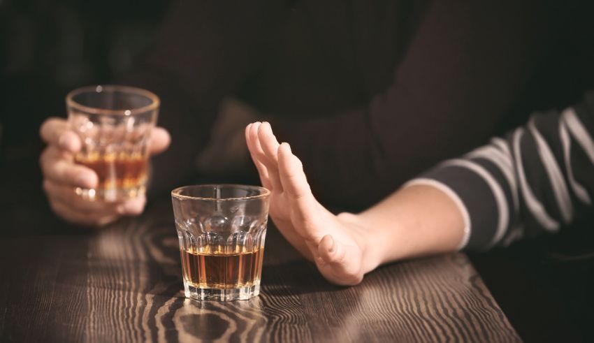 Two people holding glasses of alcohol in front of a table.
