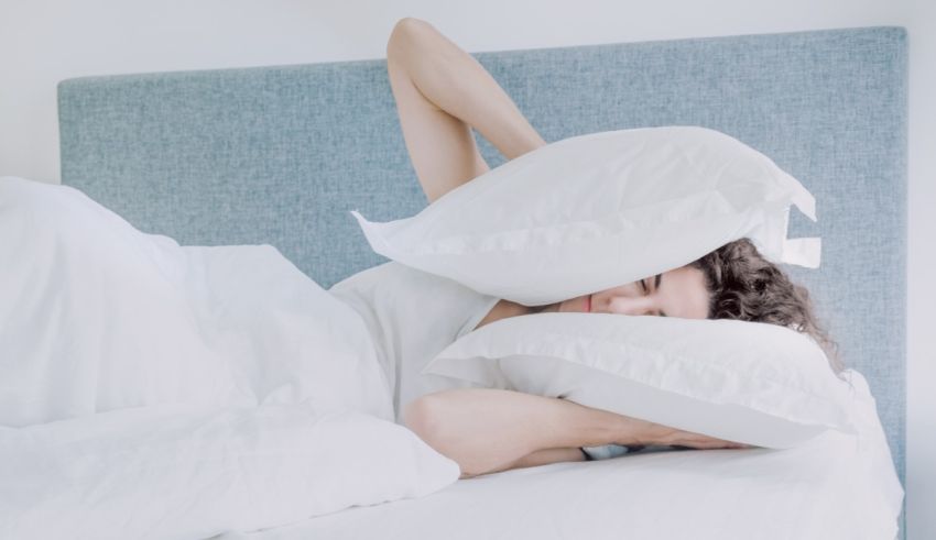 A woman is laying in bed with pillows on her head.