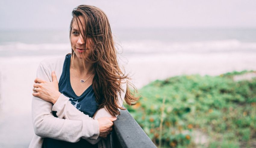 A woman leaning on a railing near the ocean.